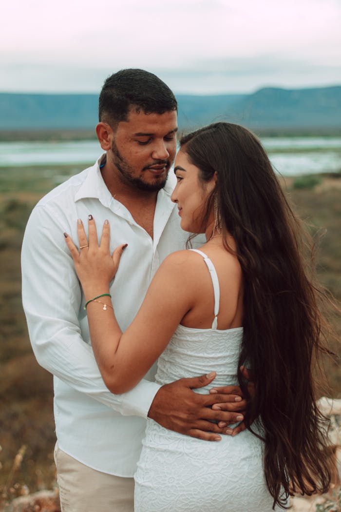 A couple embraces outdoors with a scenic Brazilian landscape backdrop, showcasing intimacy and love.