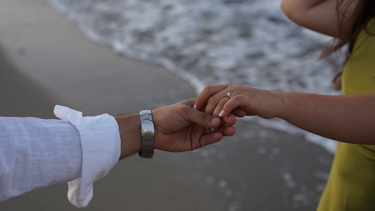 Close-up of a couple holding hands by the sea on Bozcaada Beach, Türkiye.